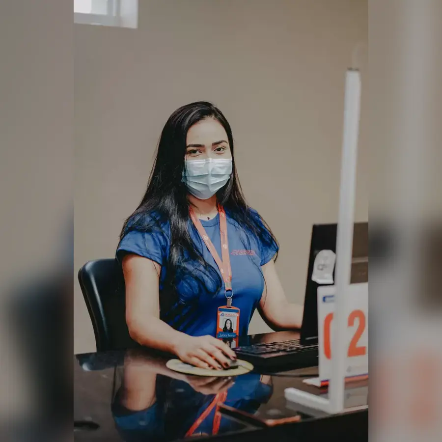 Atendente da Augustos Medicina Diagnóstica na recepção, em frente ao computador